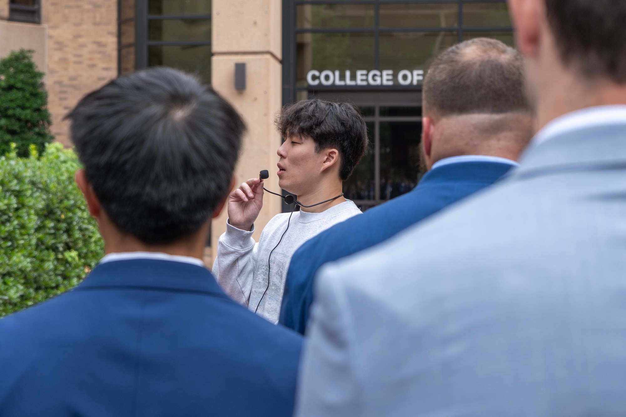 A student in a gray sweatshirt speaks into a microphone outside of the College of Dentistry building.