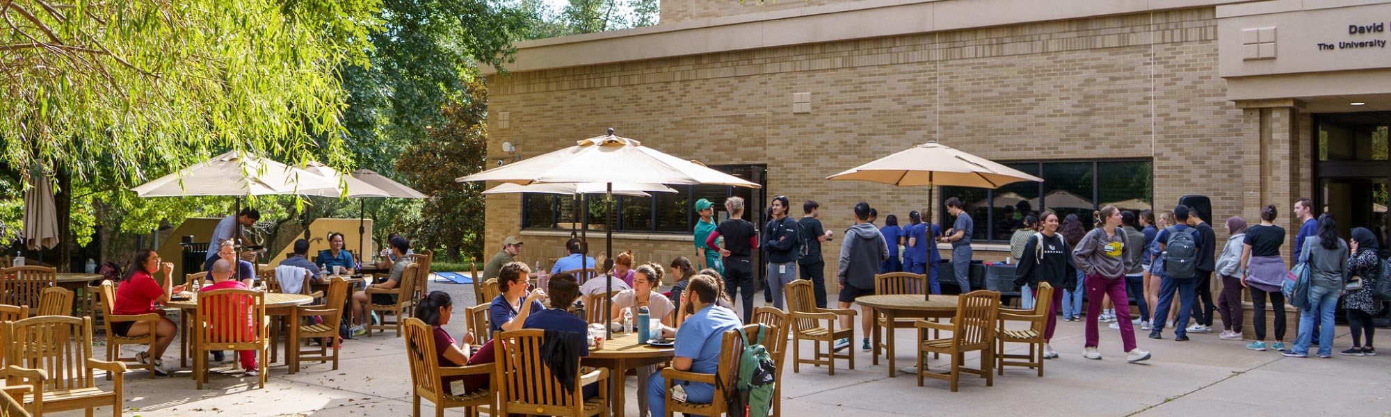 Picture of the Student Union East Patio with students at tables under umbrellas during the Summer Welcome event.