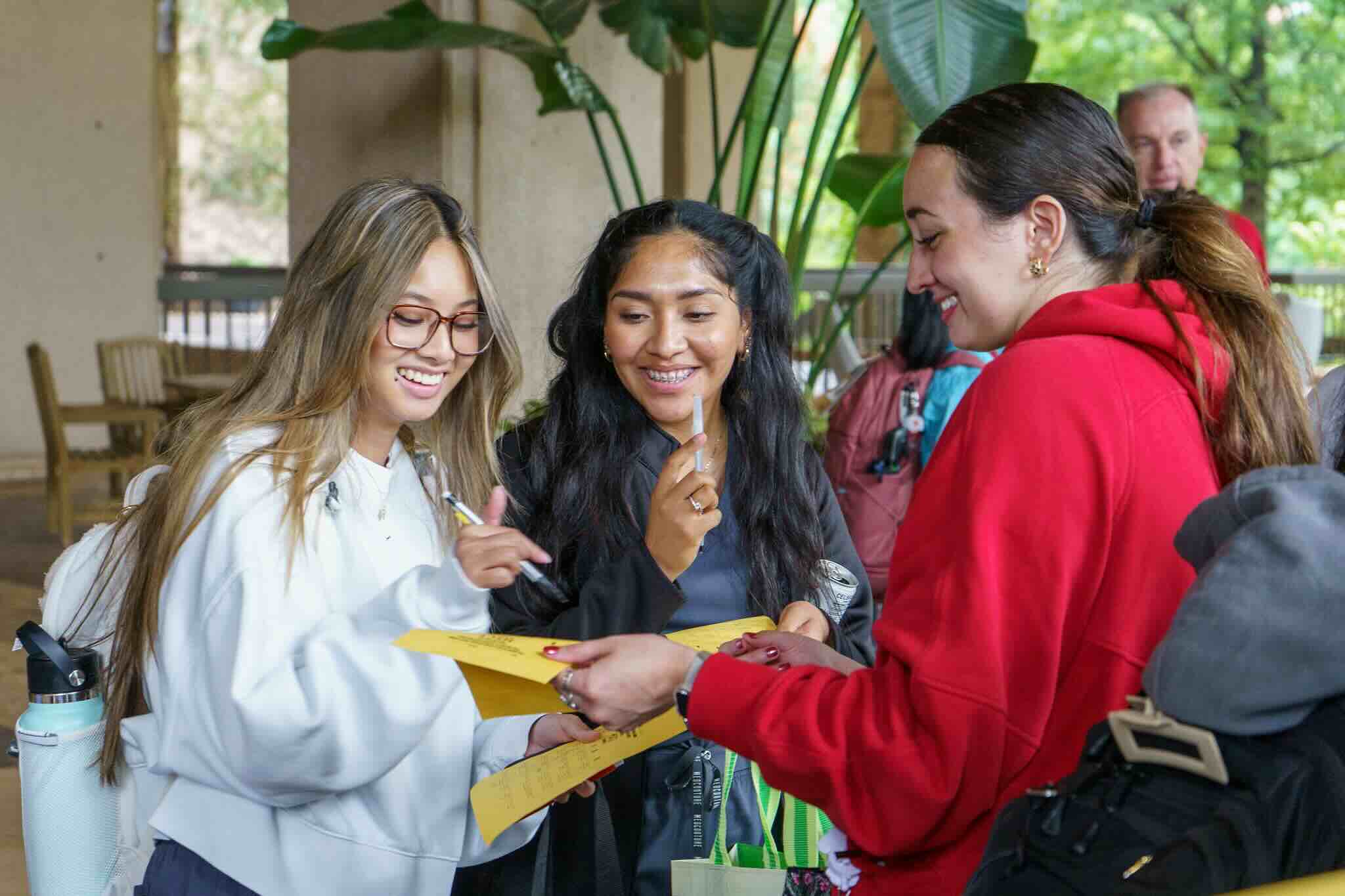 A group of three students filling out bingo cards during the Ice Cream Social.