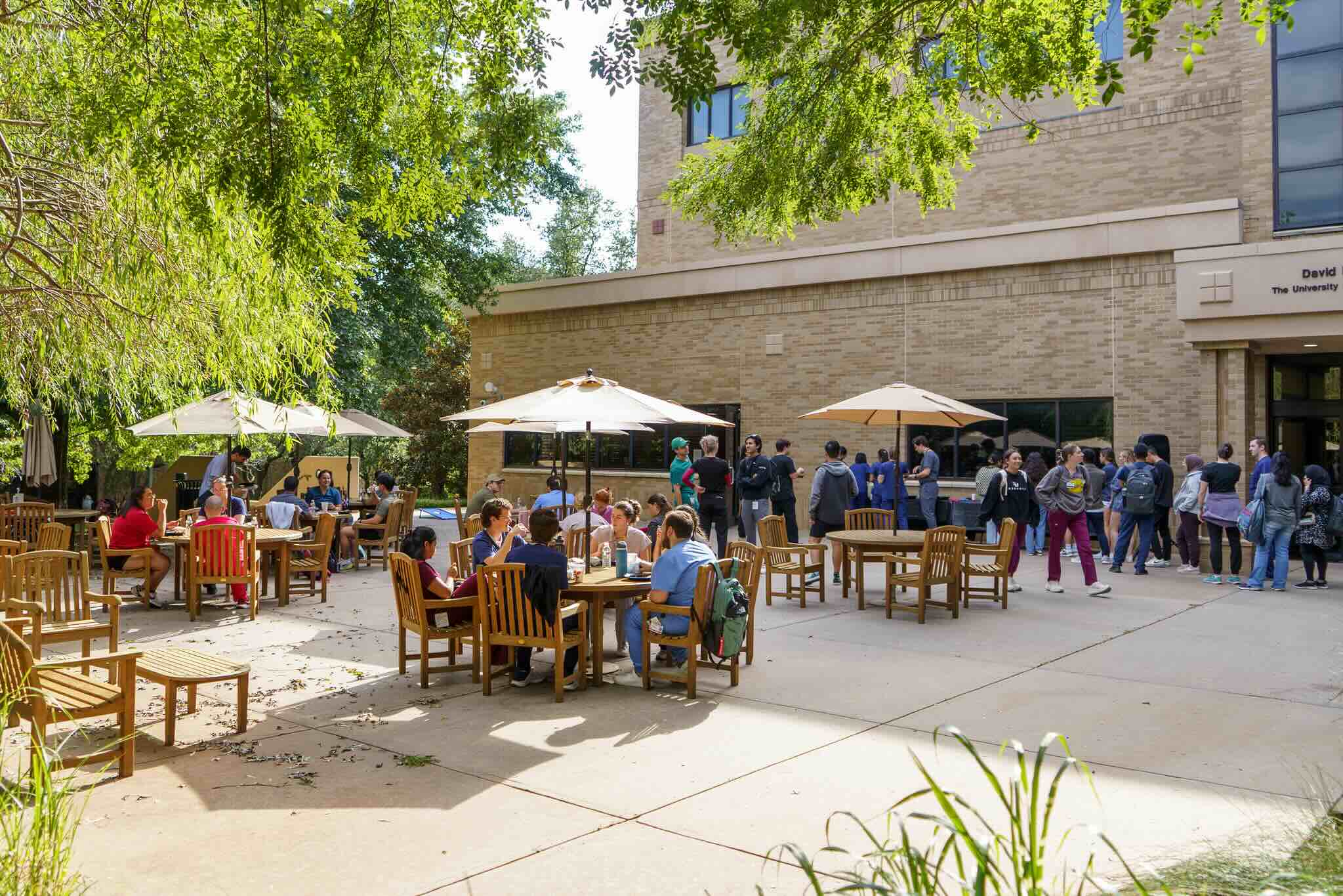 Picture of the Student Union East Patio with students at tables under umbrellas during the Summer Welcome event.