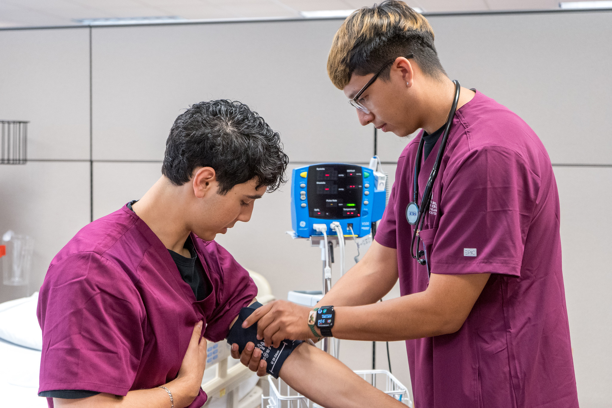 Two OU Nursing students practicing blood pressure examinations on each other.