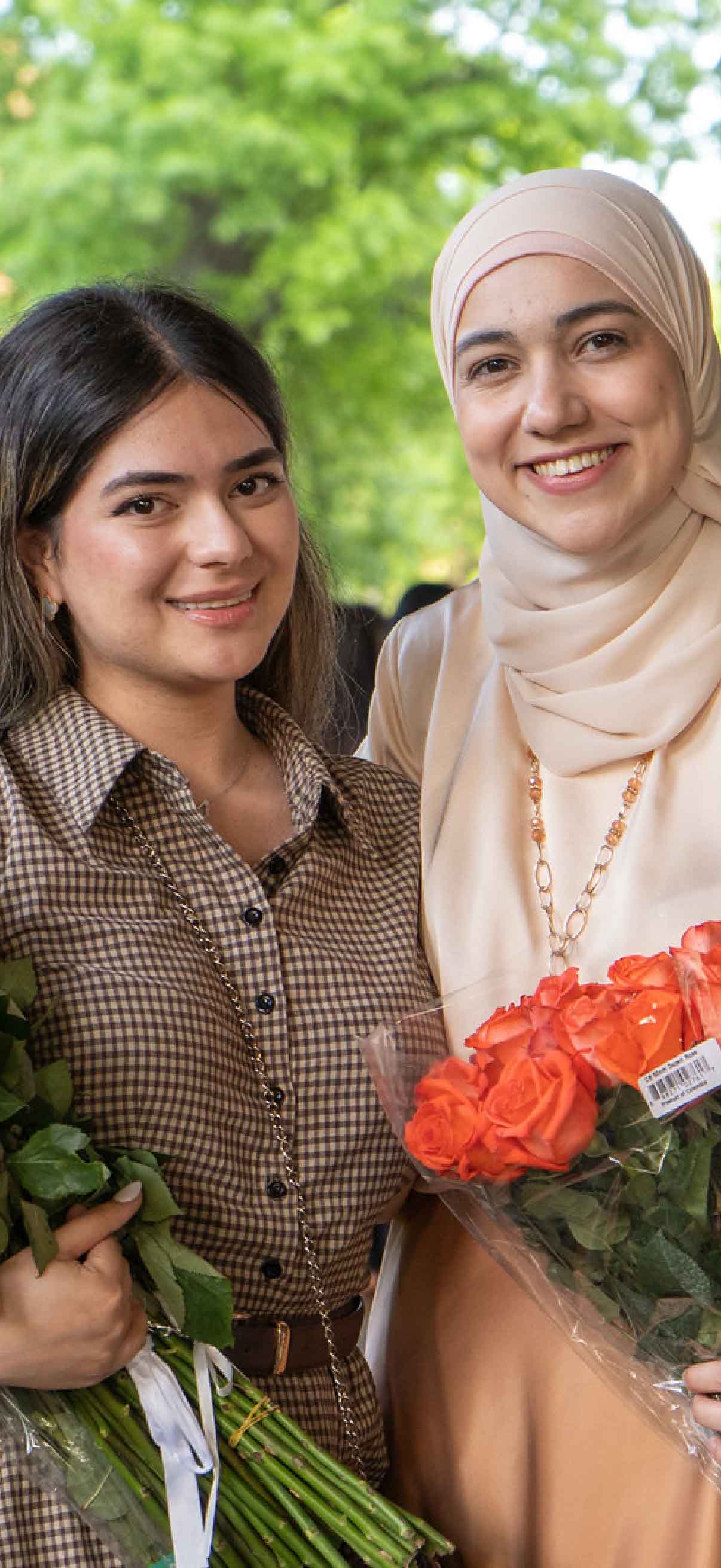 Two students embrace while holding flowers following the Student Awards Ceremony.