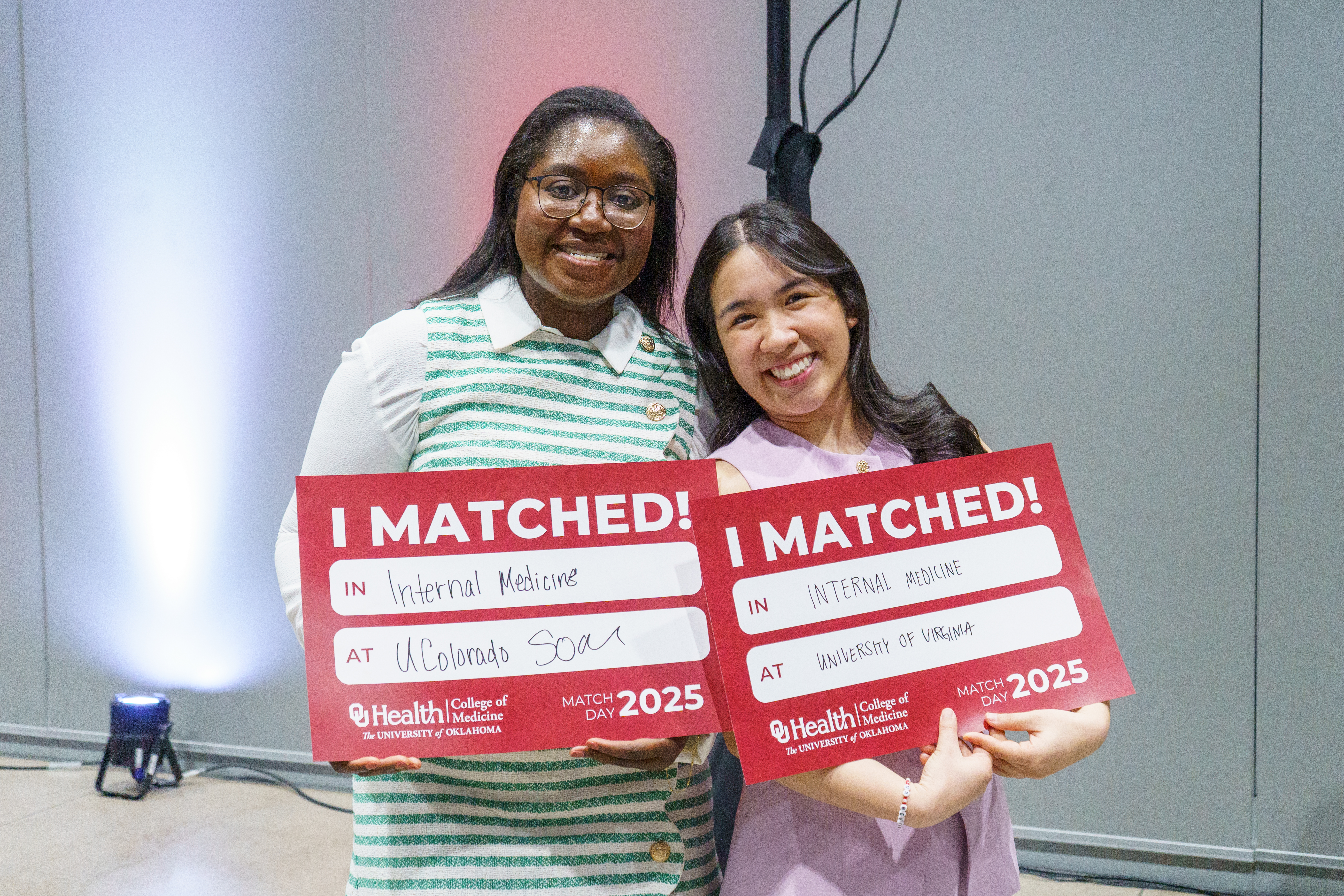 Students at the MD program match day holding up signs showing their residency site.