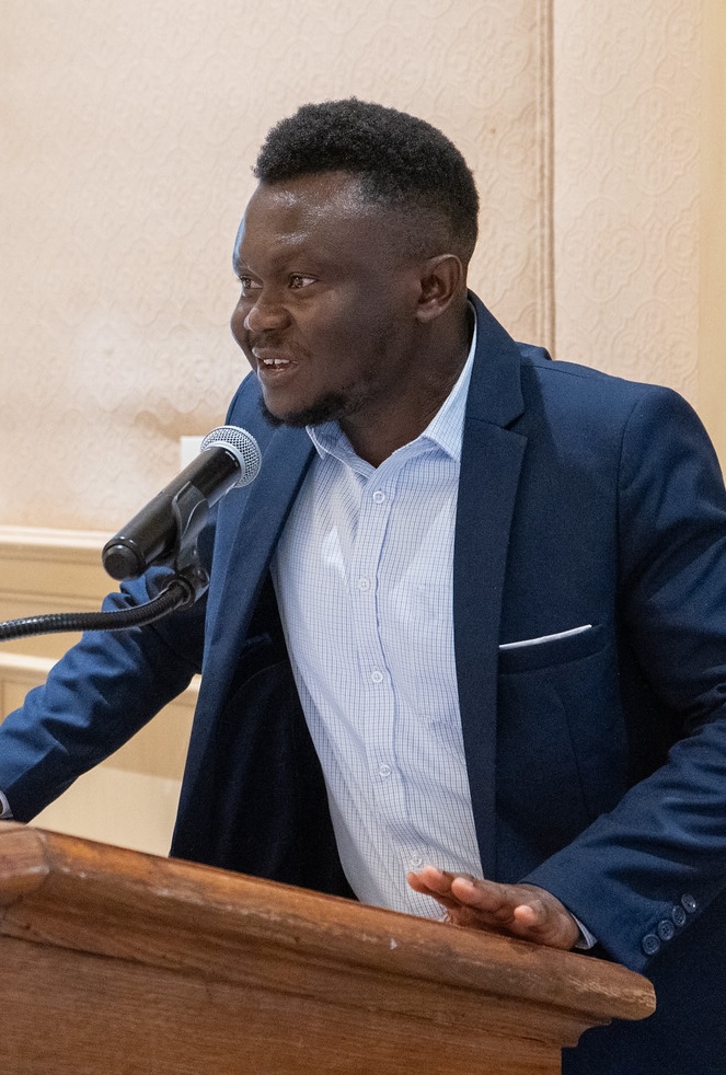 an international student in a blue suit speaking at a podium